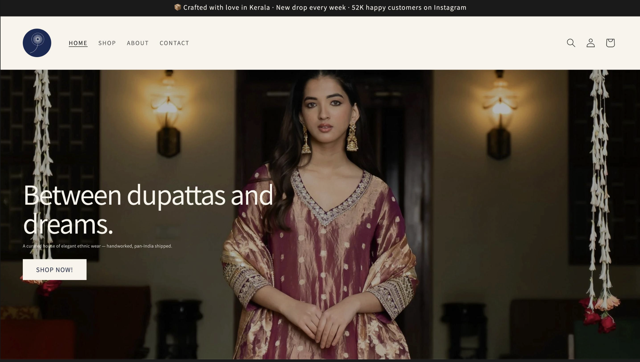 Hero section of the storefront — editorial typography, navy/ivory/copper palette, full-bleed photography of a model in a maroon-and-gold Anarkali